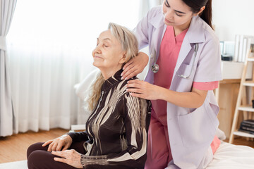Young professional confident skilled woman doctor visiting old patient lady at home for treatment control care giving. Nurse massaging senior patient. Healthcare concept