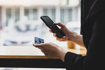 Woman using smartphone and credit card in cafe. Concept of online payment via mobile phone.