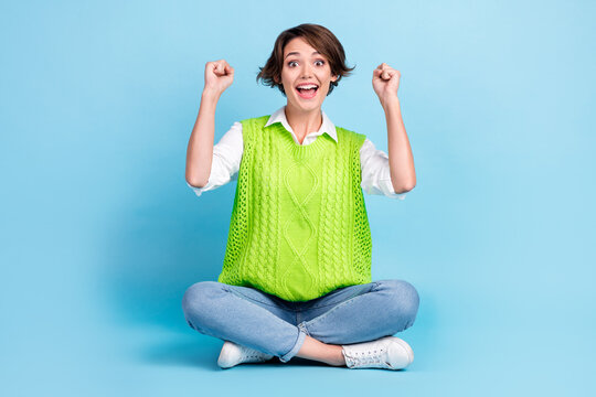 Full size photo of optimistic satisfied girl with brown hairdo wear green vest jeans scream yeah isolated on blue color background