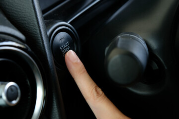Woman starts the car engine with start-stop button. Modern car interior