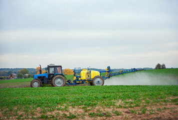 Tractor with mounted sprayer, farmer crop spraying. Tractor spraying pesticides on vegetable field with sprayer. Agricultural tractor spraying field. Tractor fertilize field pesticide and insecticide - obrazy, fototapety, plakaty