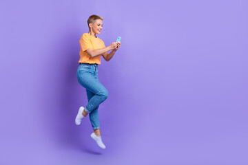 Fototapeta na wymiar Full body profile portrait of carefree energetic lady jump use smart phone empty space isolated on purple color background
