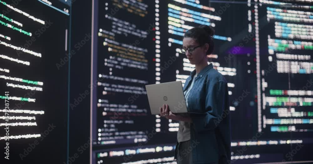 Aufkleber Portrait of Young Woman Working on Laptop Computer, Looking at Big Digital Screen Displaying Back-end Code Lines. Professional Programmer Developing a Big Data Interface Software Project