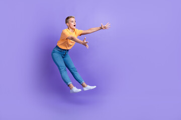 Fototapeta na wymiar Full length profile portrait of impressed person jump fall arms catch empty space isolated on purple color background