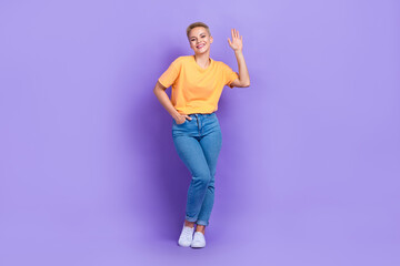Full length photo of pleasant gorgeous girl dressed jeans white sneakers weaving palm greetings say hi isolated on violet color background © deagreez