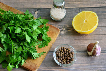 A cutting board with ingredients for a salad including parsley, lemon and salt 
