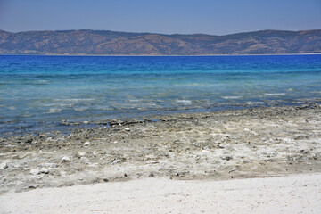 The blue sea with white sandy beach isolated and mountains on background 