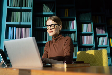 A perfectionist is a female employee of a design company working using a laptop on a desktop in a new office.