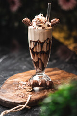 Kinder Bueno Milchshake auf rustikalem Holzbrett mit Pflanzen im Vordergrund und Hintergrund