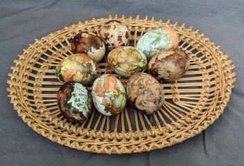 Painted Easter eggs in plated straw plate on the grey cloth background