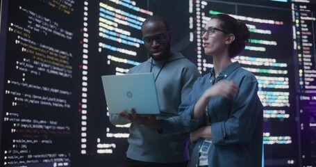 Portrait Two Diverse Developpers Using Laptop Computer, Discussing Lines of Code that Appear on Big Screens Surrounding Them. Male and Female Programmers Creating a Software Together, Fixing Bugs - Powered by Adobe