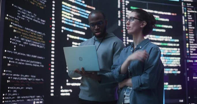 Portrait Two Diverse Developpers Using Laptop Computer, Discussing Lines of Code that Appear on Big Screens Surrounding Them. Male and Female Programmers Creating a Software Together, Fixing Bugs - Powered by Adobe