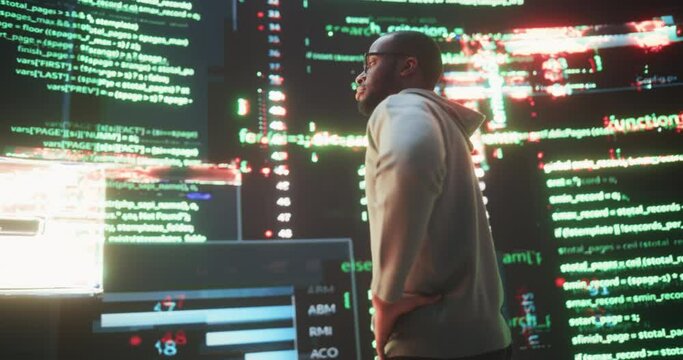 Portrait of Young Black Man Looking at Big Digital Screens Glitching While Displaying Code Lines. Worried Professional Programmer Fixing a Bug, Dealing with Crashing System, Thinking of Solutions