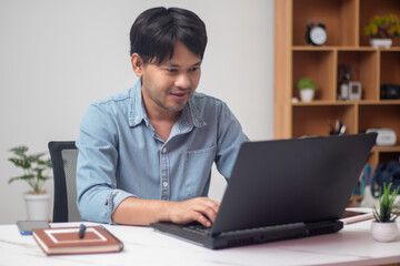 Man in denim jacket sitting and working in front of laptop