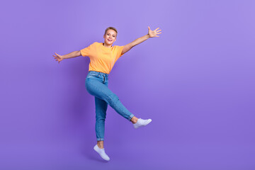 Fototapeta na wymiar Full length photo of pleasant friendly nice girl jeans white sneakers flying jumping having fun isolated on violet color background