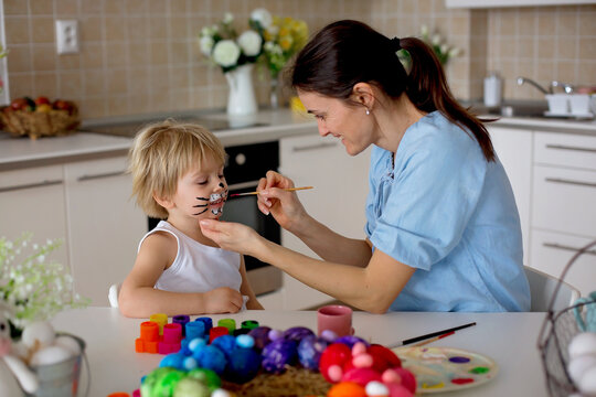 Mother painting on little blond toddler boys' face easter bunny