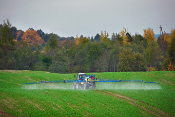 Tractor with mounted sprayer, farmer crop spraying. Tractor spraying pesticides on vegetable field...