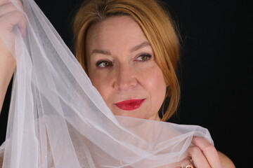 Portrait of a woman. Dark background. White cloth in hands.