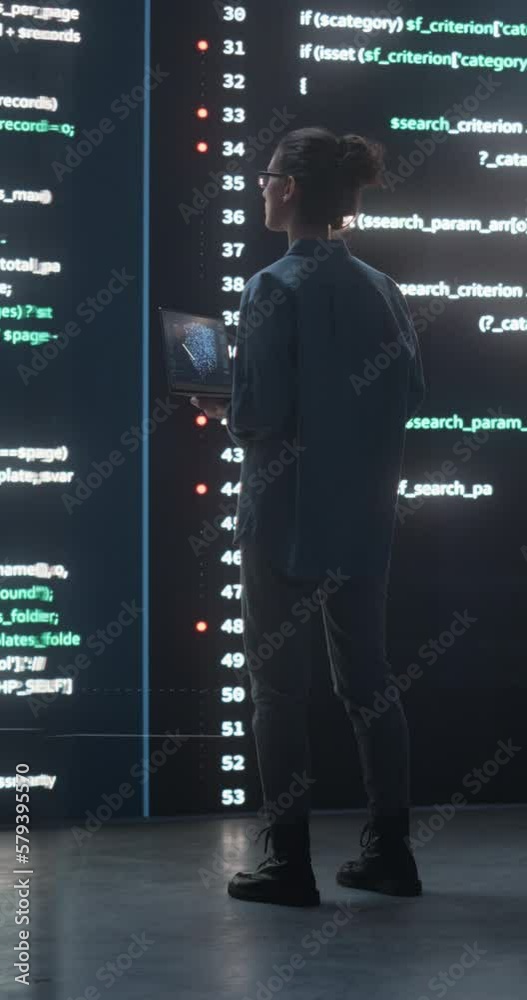 Aufkleber Vertical Screen: Portrait of Young Woman Working on Laptop Computer, Looking at Big Digital Screen Displaying Back-end Code Lines. Professional Programmer Developing Big Data Software Project