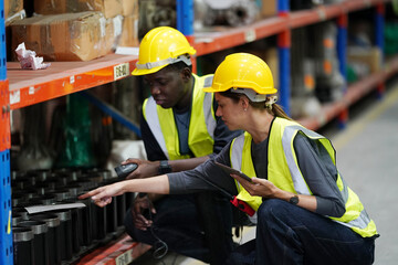 Obraz premium Warehouse workers checking the inventory. Products on inventory shelves storage. .Worker Doing Inventory in Warehouse. Dispatcher in uniform making inventory in storehouse. supply chain concept