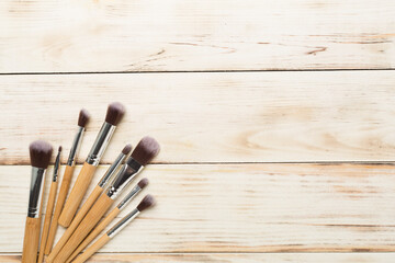 Make up brushes on wooden background, top view