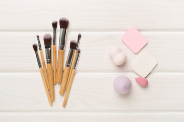Make up brush and sponge on wooden background, top view