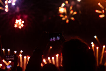 People watching fireworks. woman taking the photo of fireworks by smartphone