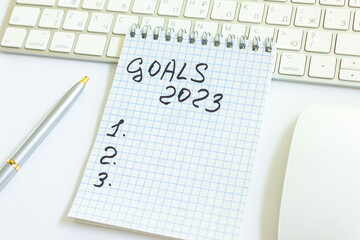 Goals 2023 writing in a notebook on a table with a keyboard from a computer