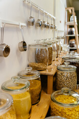 Vertical of store with zero waste goodness. Glass jars filled with cereals, pasta, nuts on a shelf.