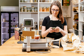 Social networks and business, online sales concept. Female owner using write message on smart phone...