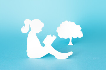 World Book and Copyright Day. silhouette of a girl reading a book and tree isolated on a blue...