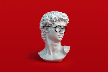 sculpture of David's head with eyeglasses on red background. Student and education concept