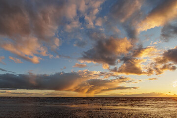 Fototapeta premium selective focus, view of setting sun and sky with clouds. nature background, peaceful abstract light. reflection in water, sand in sunlight. freedom, tourism and recreation, meditation. walk on ocean