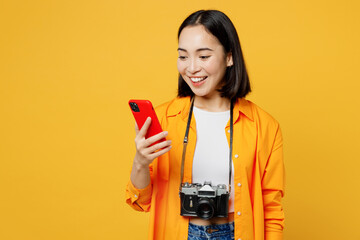 Young smiling woman wear summer casual clothes hold use mobile cell phone isolated on plain yellow...