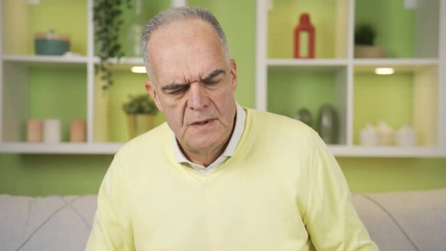 Frustrated grumpy old man getting angry at home.
The grumpy senile retired man who gets angry at everything is at home with a sullen scowl.
