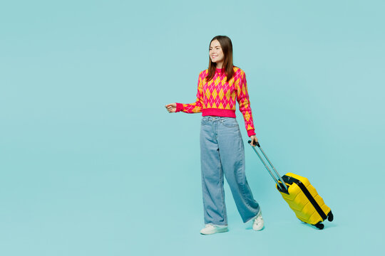 Side view traveler woman in casual clothes hold suitcase go isolated on plain pastel blue cyan background studio Tourist travel abroad in free spare time rest getaway Air flight trip journey concept