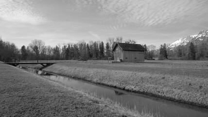 Naklejka na ściany i meble River next to wooden hut in lonely landscape in black and white