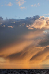 Fototapeta premium selective focus, view of setting sun and sky with clouds. nature background, peaceful abstract light. reflection in water, sand in sunlight. freedom, tourism and recreation, meditation. walk on ocean