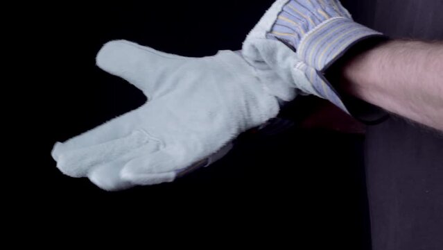 Man trying on new work gloves with dark background