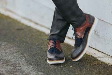 Stylish man in gray check suit pants and tricolor leather brogue shoes
