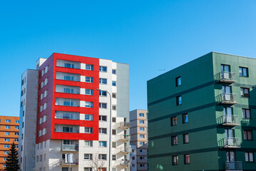 Fototapeta premium A newly built building in nice bright colors with apartments for sale.Red orange and green block of flats.Newly finished modern style apartment building in freshly renovated residential area.