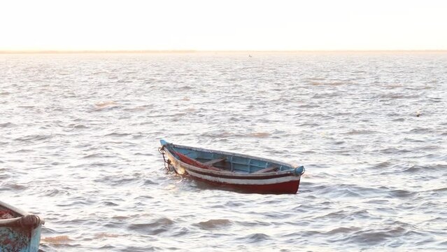 fisherman's empty boat in shore, on board a small and characteristic fishing boat in diu and daman. small solitary vessel, moored or anchored, on a calm half light and half dark sea or lake surface