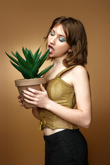 woman with stylish hairstyle posing with plant in pot