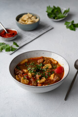 Traditional Hungarian Beef Meat Stew  Goulash made of beef chuck steak, csipetke and plenty of paprika on a light background. Hungarian traditional meal.