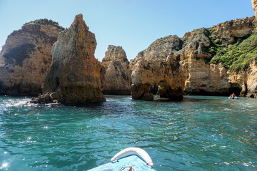 Stone Cliff caves in Portugal on a sunny day from the boat with teal water