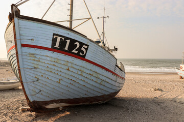 Old fisher boat stranded on the beach by the ocean at dawn 