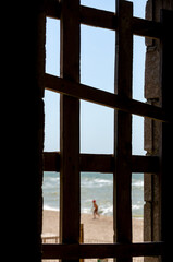 child on the beach and sea view from old wooden window