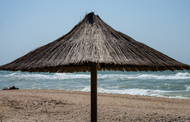 straw beach umbrella on an empty seashore on a clear day