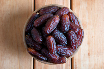 Date fruits in wooden bowl on wooden table,top view