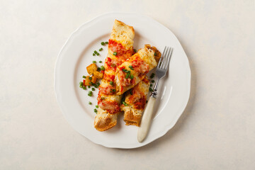 Baked pancakes with chicken in tomato sauce.